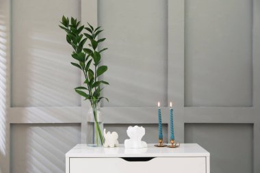 Işık duvarının yanındaki çekmecelerin üzerinde yanan mumlar olan şamdanlar.