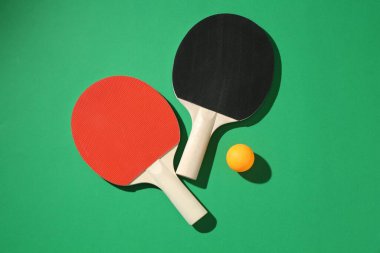 Yeşil zemin üzerinde pinpon raketleri ve top düz yatıyordu.