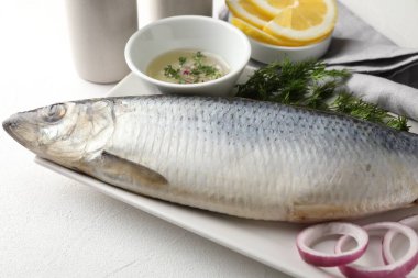 Tuzlu ringa balığı ve baharatlar beyaz masada, yakın plan.