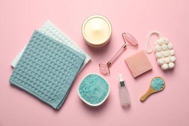 Açık pembe arka planda temiz waffle havluları ve kozmetik ürünleri, düz yatış