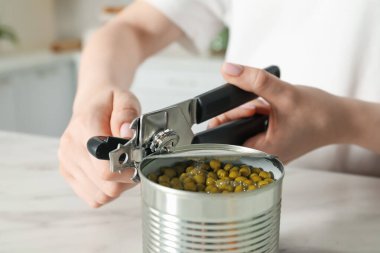 Beyaz masada konserve açacağıyla konserve açan kadın, yakın çekim