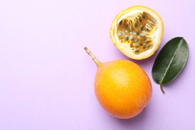 Olgun sarı çarkıfelek meyveleri ve leylak arka planda yaprak, düz uzanmış. Metin için boşluk