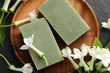 Siyah masanın üzerinde sabun ve yasemin çiçekleri yatıyordu.