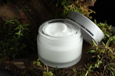 Ağaç kabuğunda bitkilerle birlikte nemlendirici vücut kremi, yakın plan.