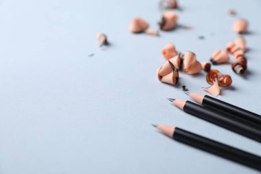 Keskin grafit kalem ve açık gri arka planda talaş, yakın plan. Metin için boşluk