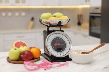 Mutfak pulları, meyveler, yulaf ezmesi ve kapalı alandaki beyaz mermer masada mezura.