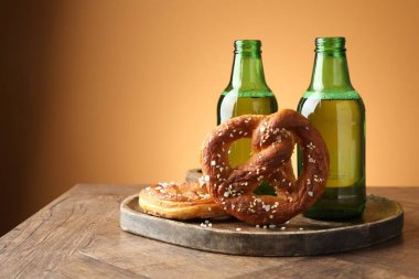 Lezzetli krakerler ve bira şişeleri ahşap masada, bej renkli arka planda, yakın plan. Metin için boşluk