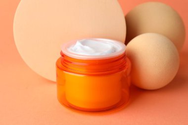 Turuncu arka plandaki kavanozda nemlendirici vücut kremi sunumu, yakın plan.