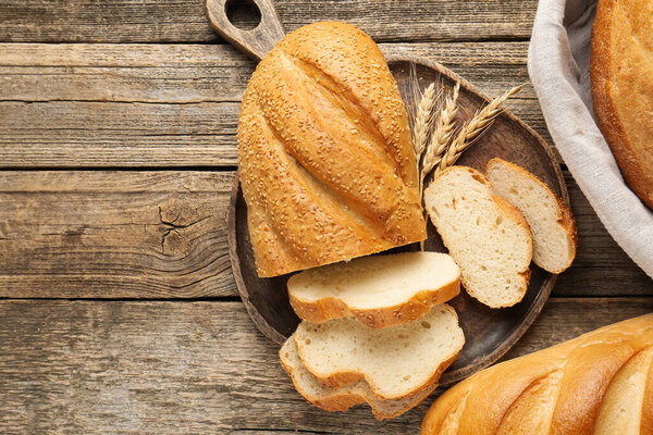 Cut bread loaf and spikes on wooden table, flat lay. Space for text