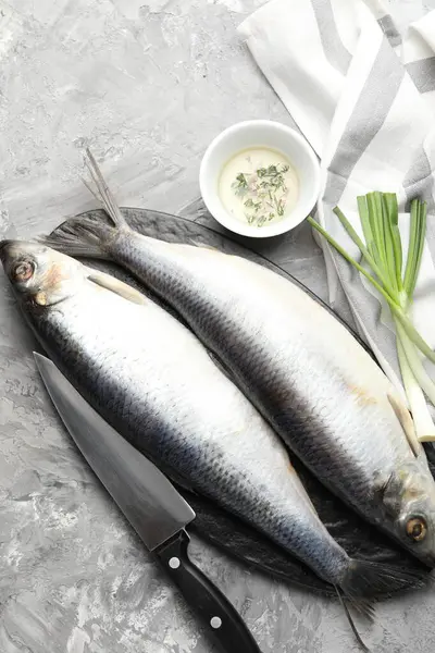 Tuzlu ringa balıkları, baharatlar ve bıçak gri masada, düz yerde.