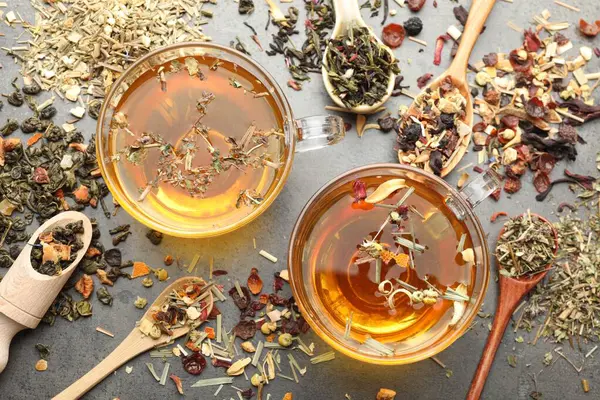 Aromatik bitkisel çay ve kuru yapraklar gri masada, düz yatıyordu.