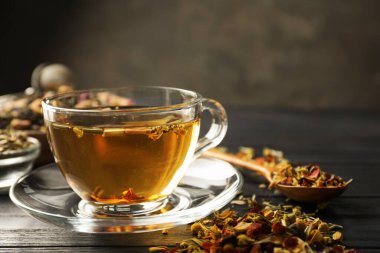 Bitki çayı ve kuru yaprakları siyah ahşap masada serinletiyor, yakın plan. Metin için boşluk