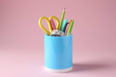 Pembe arka planda kalem tutacağında farklı bir kırtasiye