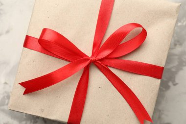 Kraft kağıdına sarılı hediye, gri desenli arka plan, yakın plan.