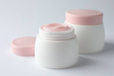 Beyaz arka planda nemlendirici vücut kremi kavanozları, yakın plan.