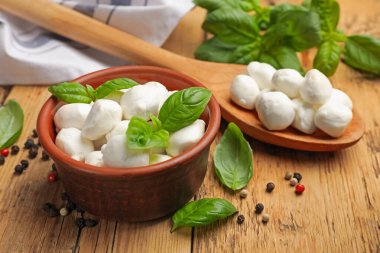 Ahşap masada fesleğenli ve biberli Mozzarella peynir topları, yakın plan.