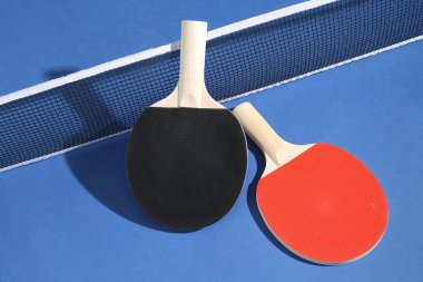 Masa tenisi raketleri ve mavi arkaplanda ağ.