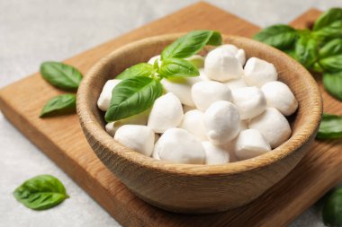 Mozzarella peynir topları ve fesleğen açık gri masada, yakın plan.