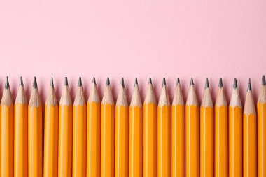 Pembe arka planda keskin grafit kalemler, düz yatış. Metin için boşluk