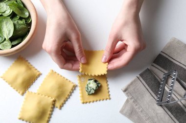 Beyaz masada peynirli ve ıspanaklı ravioli yapan kadın.