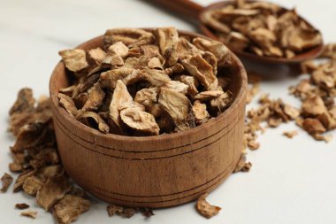 Kuru hindiba kökleri kasede ve kaşıklar beyaz masada, yakın plan.