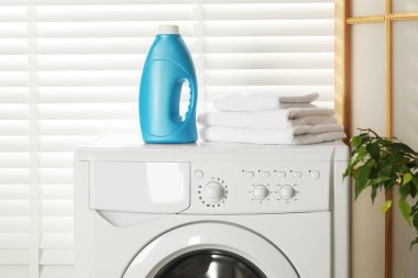 Bir şişe yumuşatıcı ve çamaşır makinesinin üzerindeki havlular.