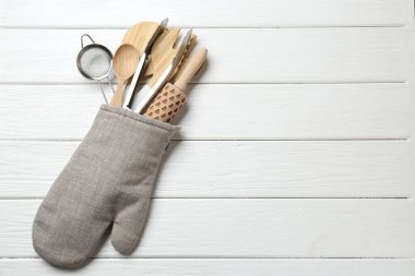 Fırın eldivenindeki farklı mutfak aletleri beyaz ahşap masa, üst manzara. Metin için boşluk