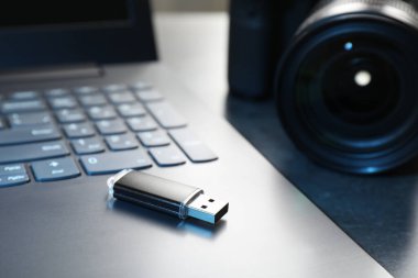 USB flaş bellek, kamera ve laptop koyu gri masada, yakın plan