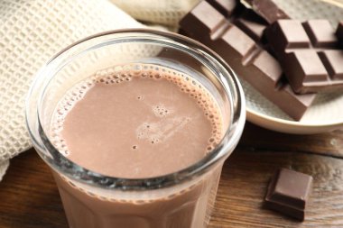 Bardakta çikolatalı süt ve ahşap masada malzeme, yakın plan.