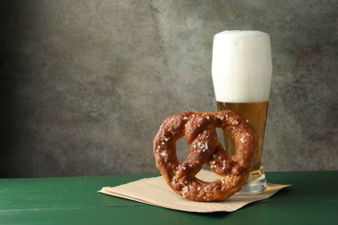 Lezzetli kraker ve yeşil ahşap masada bir bardak bira. Gri desenli arka plan, yakın plan. Metin için boşluk