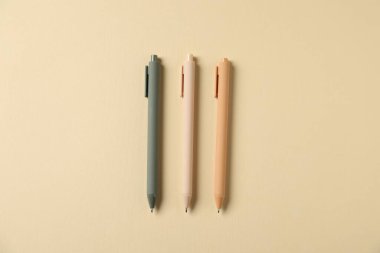 Bej arka planda şık kalemler, düz yatış