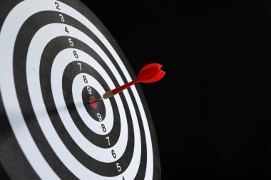 Hedef alınıyor. Siyah arka planda ok olan dart tahtası, yakın plan. Metin için boşluk