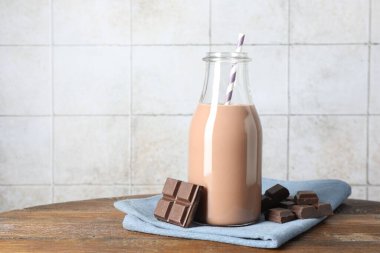 Cam şişede çikolatalı süt ve ahşap masada malzeme, metin için yer.