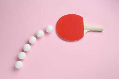 Masa tenisi raketi ve toplar pembe arka planda, düz yatıyordu.