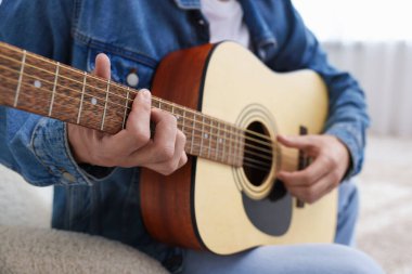 Sandalyede gitar çalan adam, yakın plan.