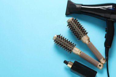 Açık mavi arka planda farklı saç şekillendirme araçları, düz yatış. Metin için boşluk