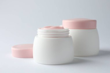 Beyaz arka planda nemlendirici vücut kremi kavanozları, yakın plan.