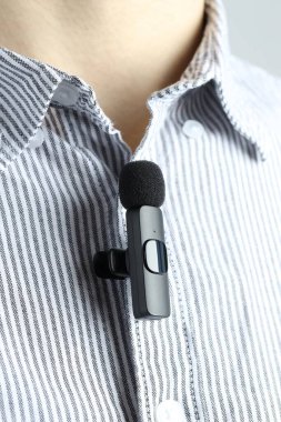Gömleğine mikrofon takmış bir adam, yakın plan.