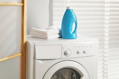 Bir şişe yumuşatıcı ve çamaşır makinesinin üzerindeki havlular.