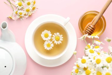 Fincanda nefis papatya çayı, taze çiçekler ve pembe arka planda bal, düz uzanma