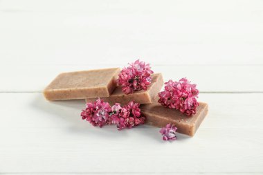Sabun çubukları ve leylak çiçekleri beyaz ahşap masada, yakın plan.