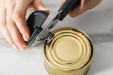 Beyaz masada konserve açacağıyla konserve açan kadın, yakın çekim