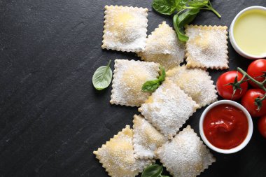 Pişmemiş ravioli, sos, domates ve fesleğen, siyah masa, düz yatak. Metin için boşluk