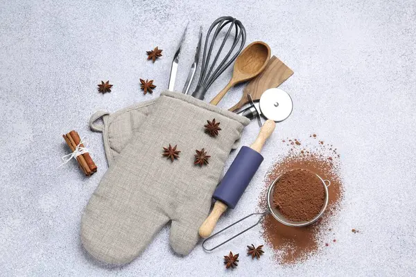 Farklı mutfak aletleri fırın eldiveni, kakao tozu, tarçın ve anason yıldızları ışık masasında, düz yatıyordu.