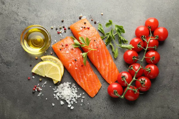 Deniz ürünleri. Somon fileto, domates, limon dilimleri, yağ ve baharatlar gri desenli masada, düz yerde.