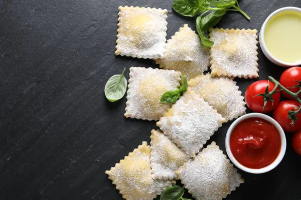 Pişmemiş ravioli, sos, domates ve fesleğen, siyah masa, düz yatak. Metin için boşluk
