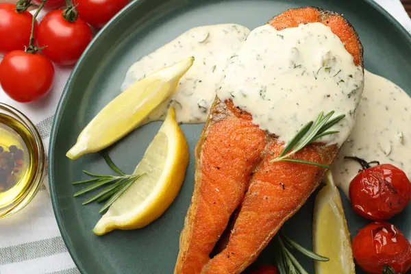 Deniz ürünleri. Sos, domates, biberiye ve limonla servis edilen lezzetli somon bifteği.