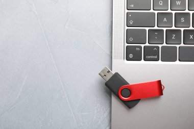 Modern flaş bellek ve laptop açık gri masada, üst görünümde. Metin için boşluk