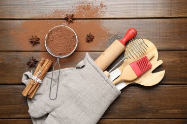 Farklı mutfak aletleri fırın eldivenlerinde, kakao tozu, tarçın ve anason yıldızları tahta masada, düz yerde