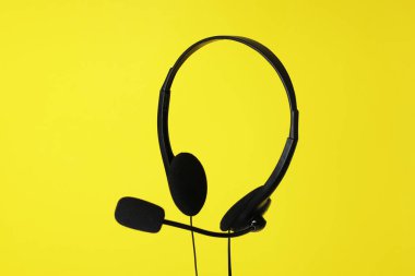 Sarı zemin üzerinde mikrofon olan kulaklık.